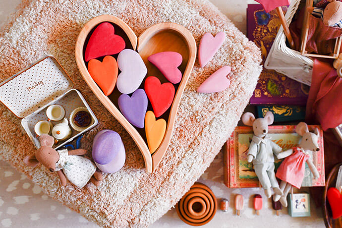 Grimm's wooden toy heart in vibrant pink and red colors with a maileg mouse on a plush blanket