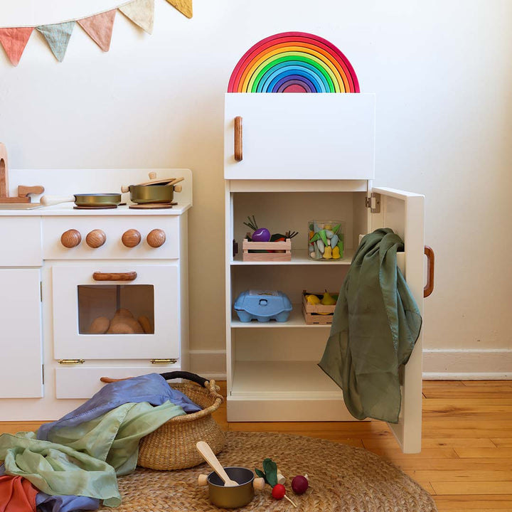 Children's play kitchen set with toy stove, rainbow decoration, and shelves.