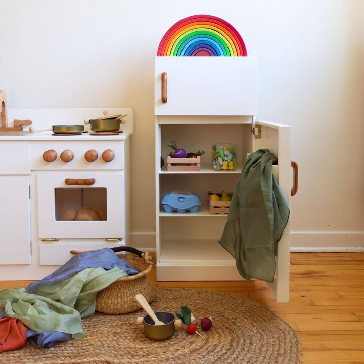 Children's play kitchen set with a rainbow decoration on a white wall