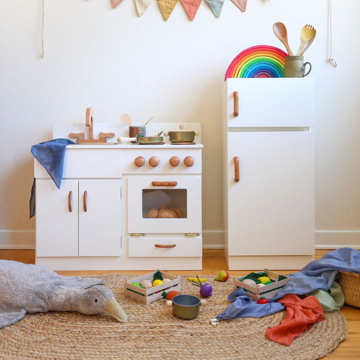 Children's wooden play kitchen set with toys on a wooden floor