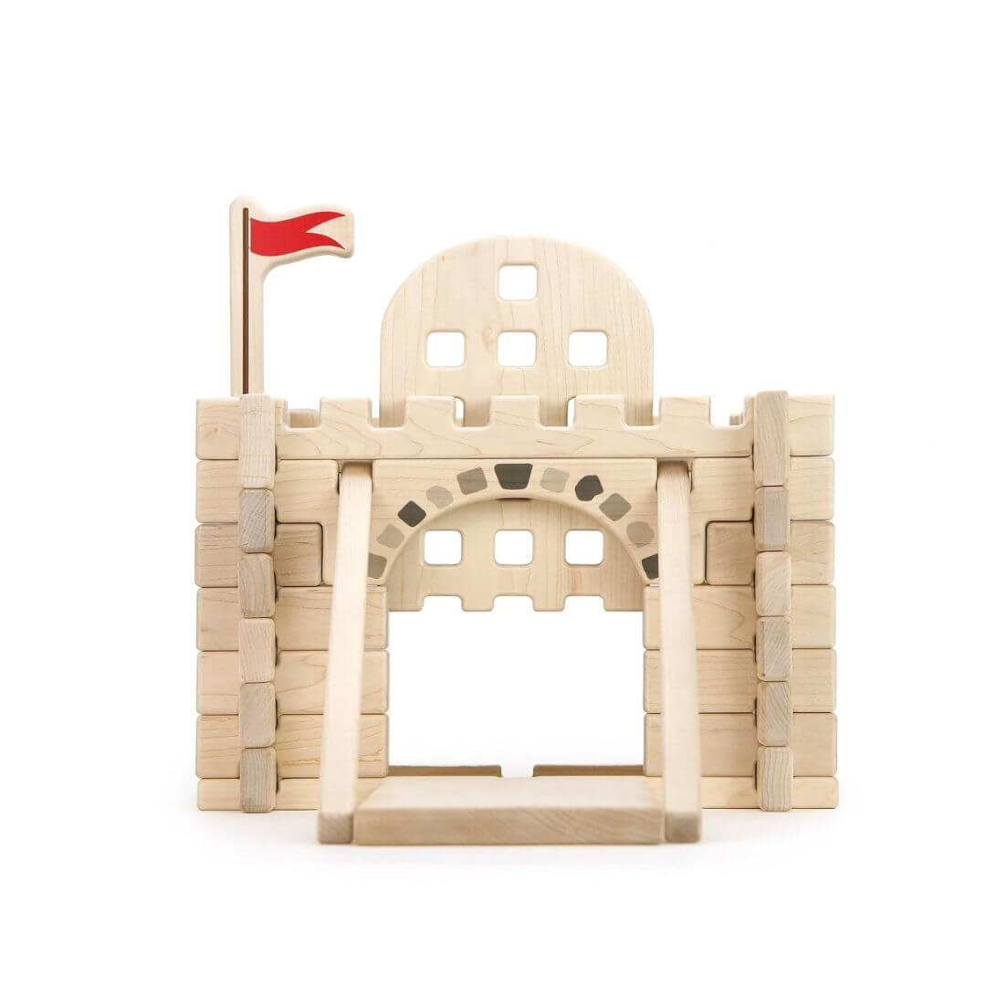 Everwood Friends Wooden Notch Blocks Castle Gate Set assembled into a medieval castle entrance made from natural hard maple wood. The detailed structure features interlocking wooden walls, crenellated battlements, a red flag flying above the castle, and a working portcullis gate beneath a decorative stone-patterned archway - Bella Luna Toys