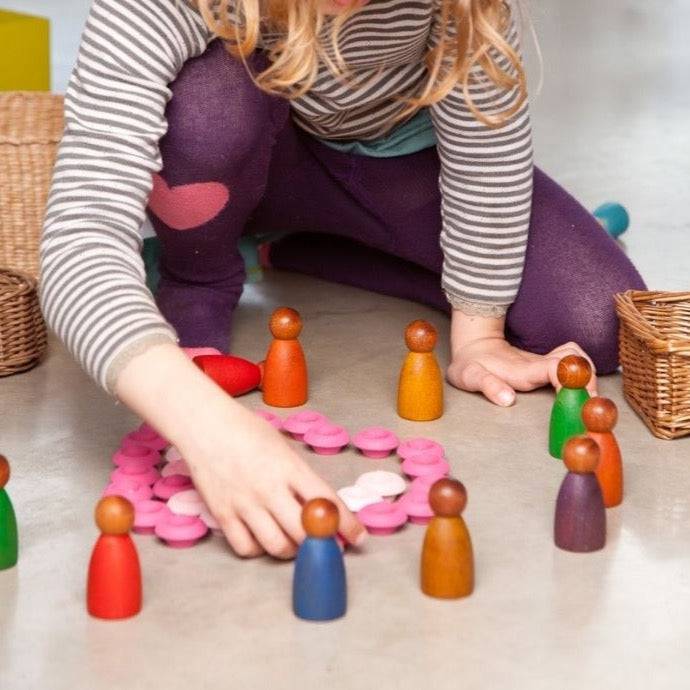 Child playing with Grapat wooden toys, including Dark Wood Warm Color Nins Peg People