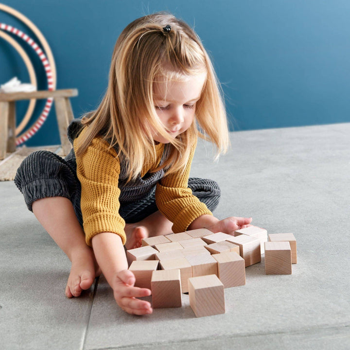 Image of a child gathering wooden cubes from the Clever UP! Unit Wooden Building Blocks set.