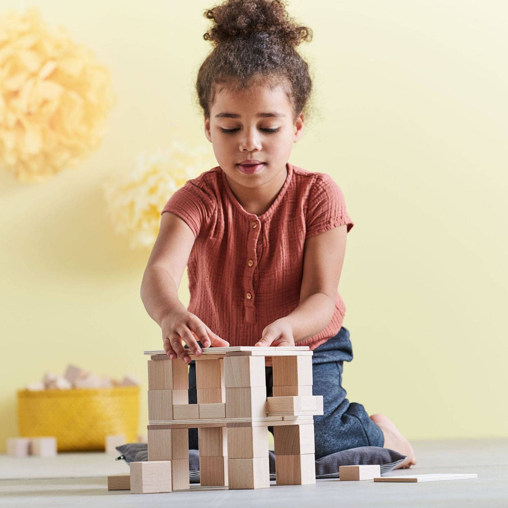Image of a child stacking blocks from the Clever Up! Unit Wooden Building Blocks set into a tower.