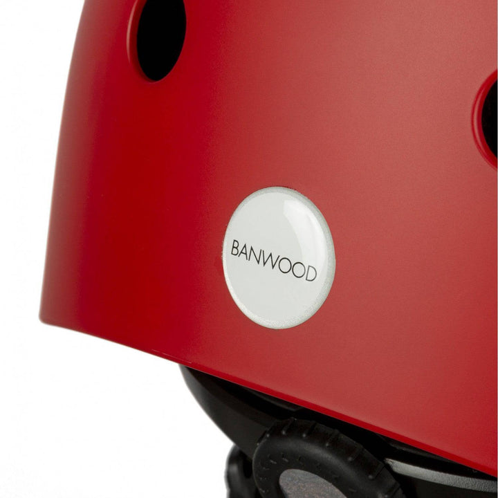 Close-up of Banwood Red kids bike helmet with ventilation holes, size adjustment knob and round Banwood logo