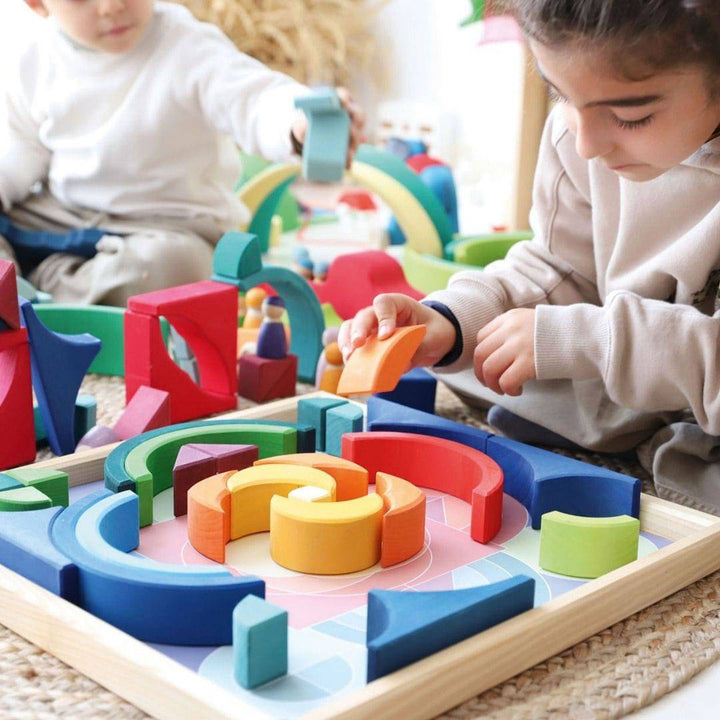 a scene with a child putting the blocks back in the tray, like a puzzle, with another child playing in the background with other Grimm's blocks