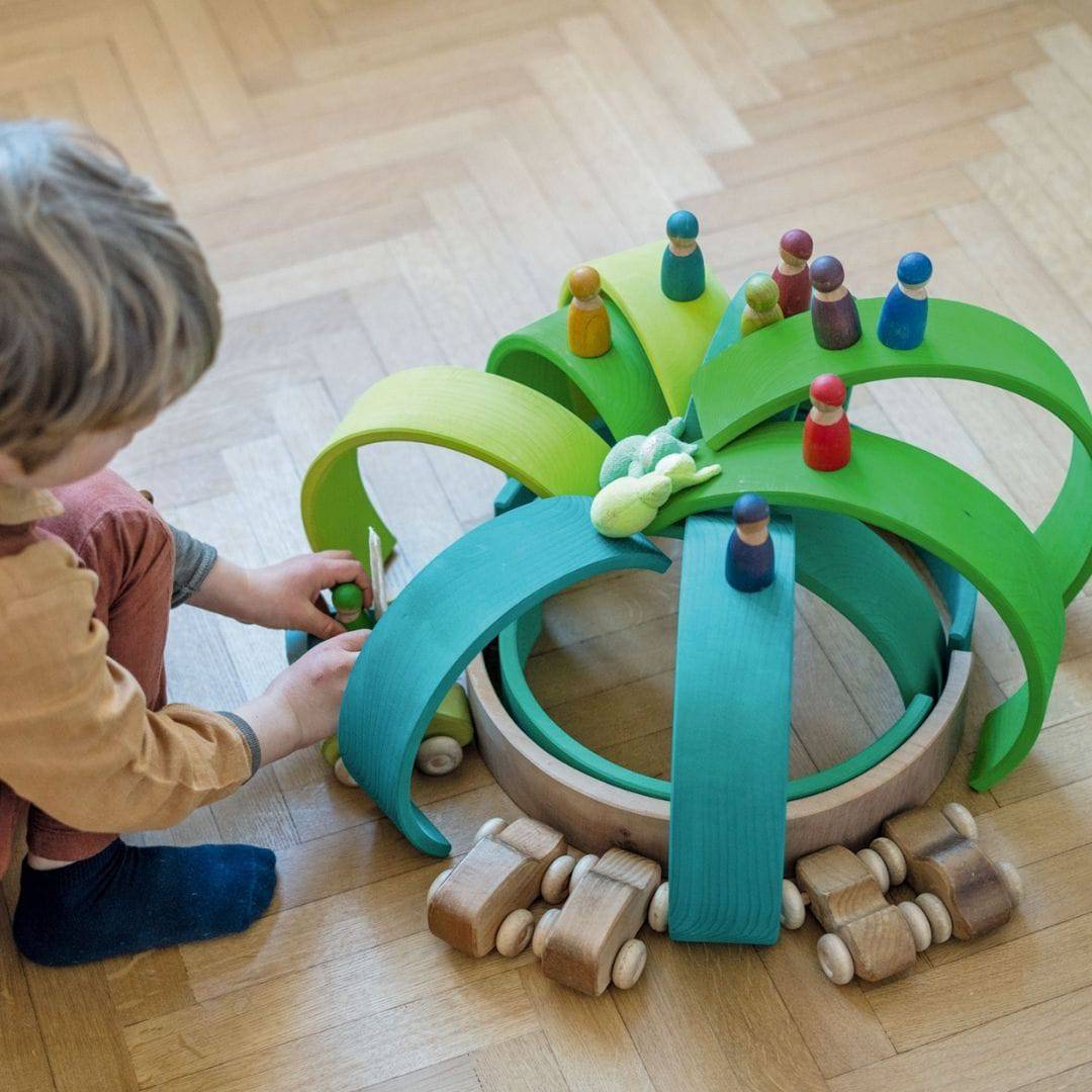 child playing with Grimm's Wooden Rainbow Meadow Green Stacking Tunnel