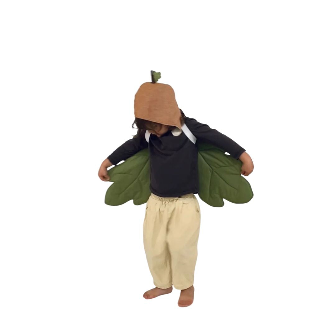 Child standing, wearing brown acorn hat with green acorn leaf wings- Bella Luna Toys